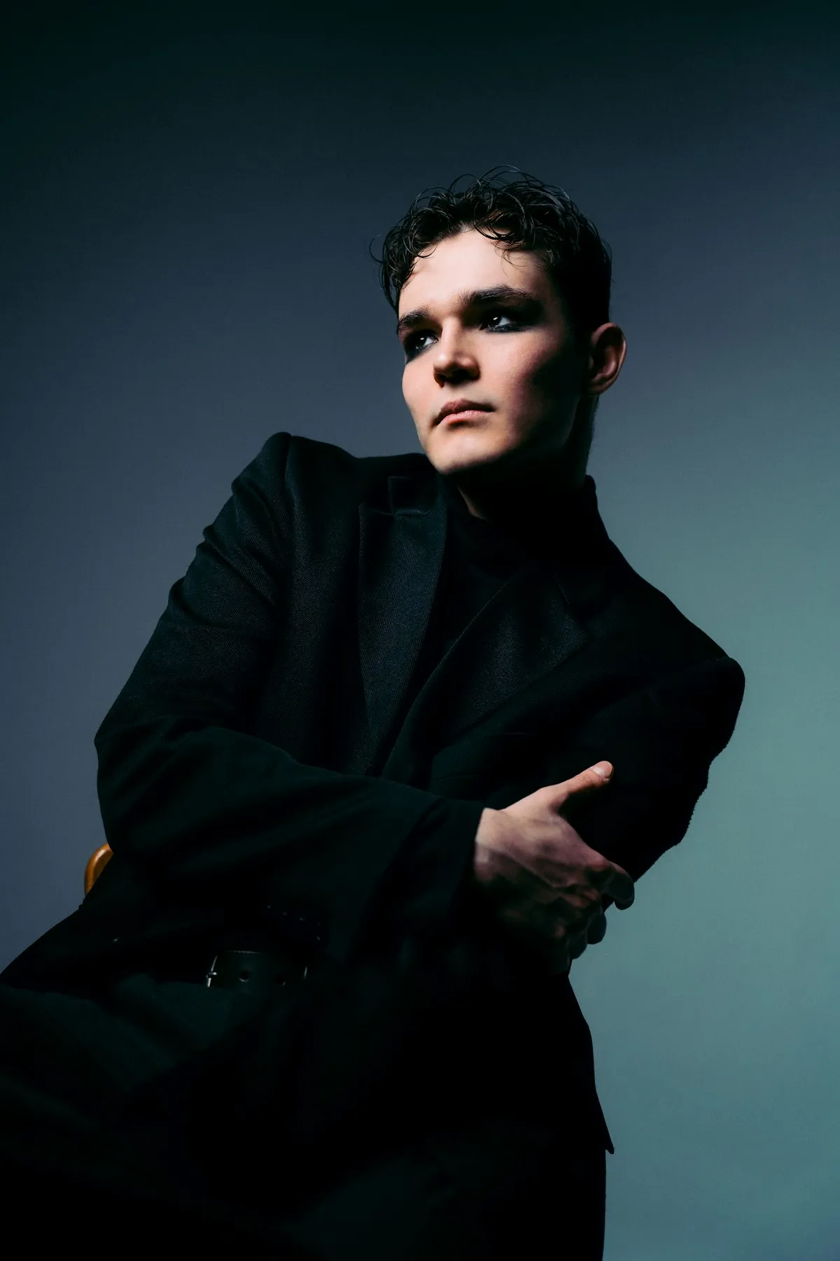 Talent in a black coat under dramatic editorial light